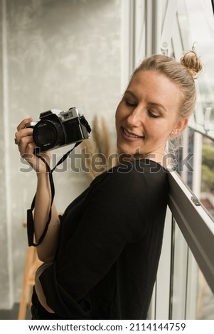 Woman with a camera in her hand. Professional, serious and elegant woman photographer.