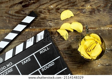 clapper board of video cinema in studio, potato chips in metal bowl on wooden table