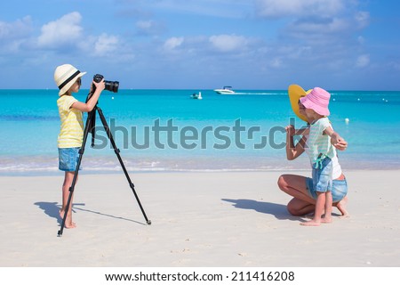 Little girl making photo of her mom and sister at the beach