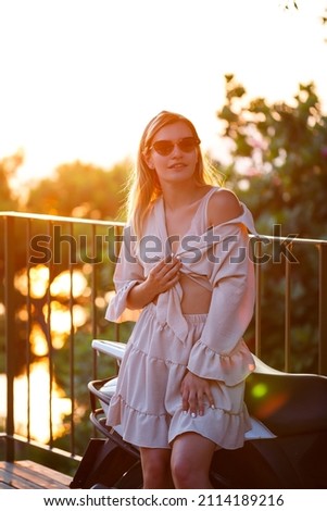 A beautiful woman at sunset stands on a terrace overlooking the sea. High quality photo
