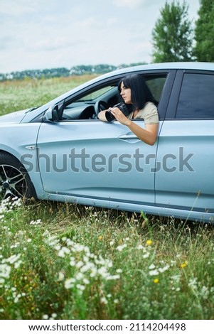 Woman photographer sitting in the car and photographing a flower field landscape