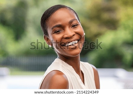 Portrait of smiling middle aged african woman looking at camera. Cheerful black mid adult woman smiling outdoor. Close up face of beautiful black lady laughing at park. Royalty-Free Stock Photo #2114224349