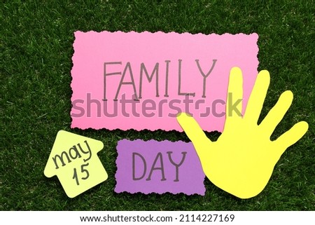 Cards with text Family Day and paper palm on green grass, flat lay