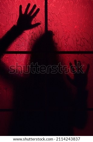 Creepy silhouette of a man behind a closed door in red light