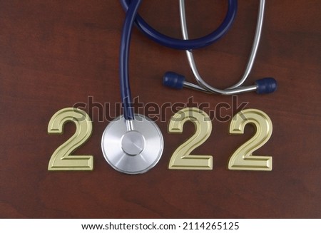 Stethoscope and numbers 2022 on wooden table. 