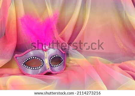 Photo of elegant and delicate purple Venetian mask over colorful chiffon background