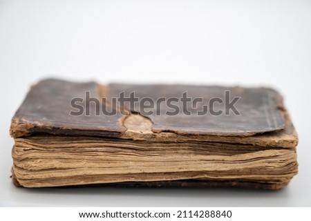 An Old Brown Book Sits Facing Us Closed With Leather Cover Concealing The Old English Words Printed Within. The edges of pages are protruding from beneath the cover. Royalty-Free Stock Photo #2114288840