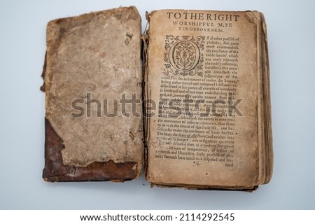 A Tattered Ancient English Book Sits Open.  Royalty-Free Stock Photo #2114292545