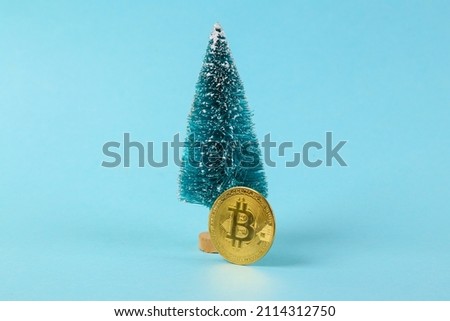 Mini Christmas tree with bitcoin on blue background. Minimal financial layout