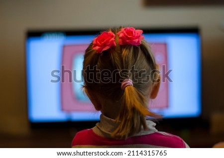Little girl watching too many tv show cartoons at home close to television screen