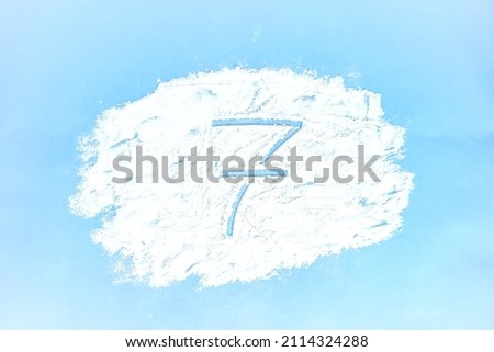 A picture of a cloud made with flour on a blue background and the number 7 drawn on it