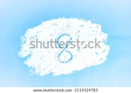 A picture of a cloud made with flour on a blue background and the number 8 drawn on it