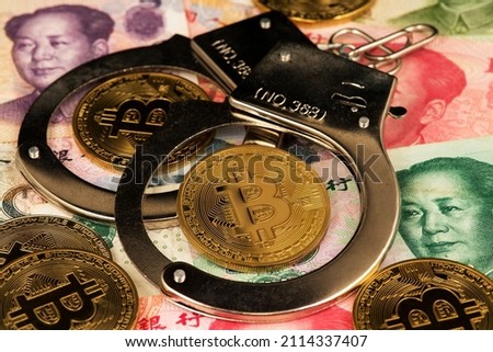Background with Bitcoin cryptocurrency coins and police handcuffs on China Yuan banknotes. Bitcoin with Chinese banknotes. China Bitcoin Cryptocurreny