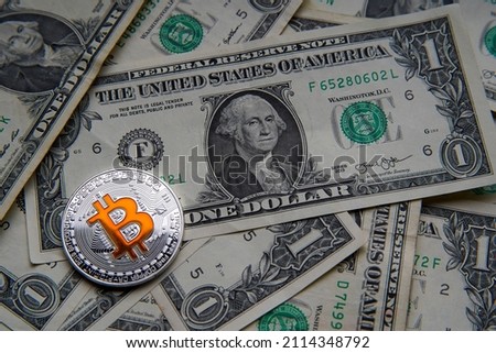 Pile of American dollar cash. Next to it is a silver bitcoin digital cryptocurrency coin. Bank image and photo background. 