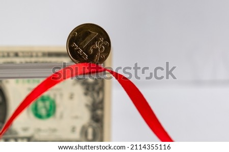 One ruble coin close-up on blurred background of red ribbon and One dollar banknote Royalty-Free Stock Photo #2114355116