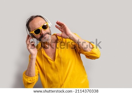 Stylish senior man enjoying music on earphones with sunglasses