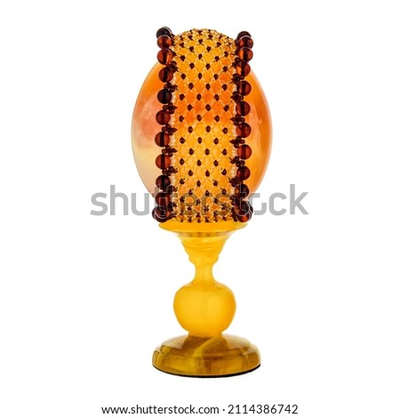 Decorative Honey Amber Easter Egg on stand isolated on white background. Polished Festive decoration for interior design.
