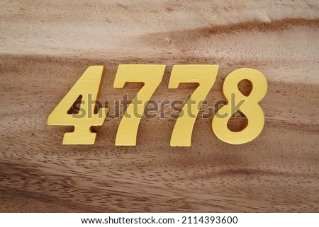Wooden Arabic numerals 4778 painted in gold on a dark brown and white patterned plank background.