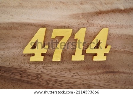 Wooden Arabic numerals 4714 painted in gold on a dark brown and white patterned plank background.