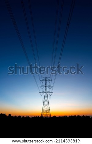 Silhouette High Voltage Electric Transportation.High voltage transmission pole against sunset background. Royalty-Free Stock Photo #2114393819
