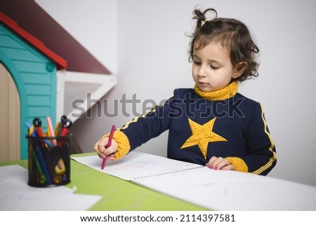 Little girl drawing at her green work table