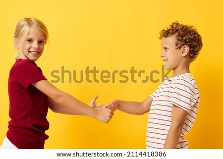 picture of positive boy and girl standing side by side posing childhood emotions yellow background