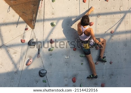 the girl climbs on the climbing wall. rock climbing as a type of active recreation in the city. playing sports in nature.
 Royalty-Free Stock Photo #2114422016