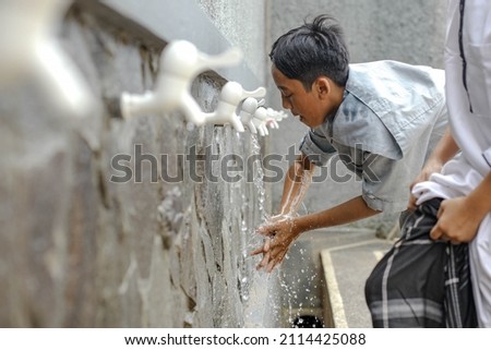 A islamic boarding school student is doing ablution washing his hand Royalty-Free Stock Photo #2114425088