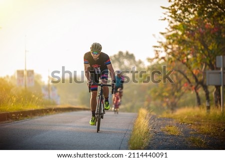 cyclist leads in action,Front view man riding bicycle in the morning Royalty-Free Stock Photo #2114440091
