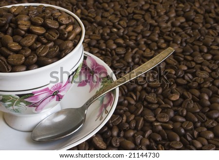 The cup of coffee surrounded by coffee beans