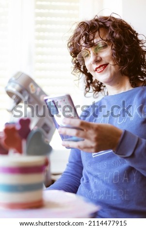 Smiling caucasian woman taking a picture of a cake with her mobile phone. Selective focus.