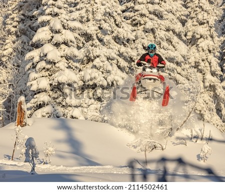 snowmobile jump straight up. the guy is flying and jumping on a snowmobile on a background of blue sky leaving a trail of splashes of white snow. bright snowmobile and suit. No brands. copy text