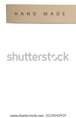 Rectangular cardboard tag for clothes with inscription in middle indicating that item is hand made put horizontally on white background. Tag mock up. Copy space.