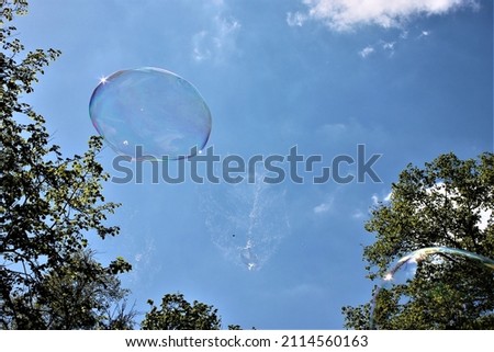 The soap bubble against the blue sky, the bubble bursting