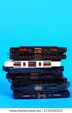 Stack of old vintage retro audio cassette tapes isolated on a blue background with copy space