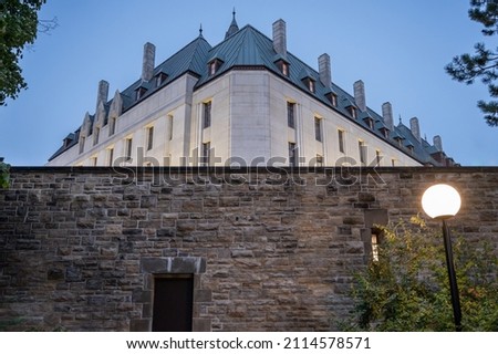 A Large Building Presides Over A Stone Wall Lit Up By A Single Lamp. This is the Supreme Court of Canada, located in Ottawa, Ontario, Canada. Royalty-Free Stock Photo #2114578571