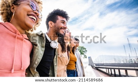 Diverse young friends hugging each other outdoors - Multiethnic group of people  standing together showing unity and teamwork - Support and community concept Royalty-Free Stock Photo #2114589686