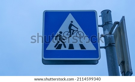 Bike and Pedestrian Crossing Sign against dusk Sky Background. Sign showing pedestrian and bike path crossing. Space for text. Urban concepts.