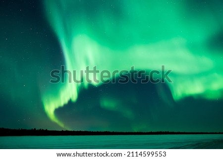 Northern lights, aurora borealis in the night sky over frozen lake in Lapland, Finland Royalty-Free Stock Photo #2114599553