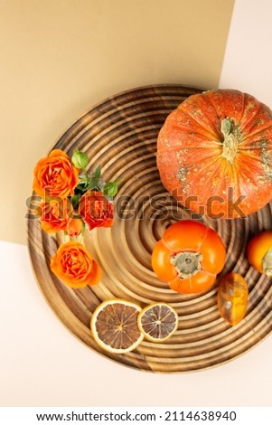 Pumpkin and persimmon on a wooden background with roses. High quality photo