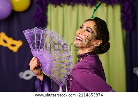 Young happy woman wearing carnival costume and make-up during Mardi Gras celebration carnival. 