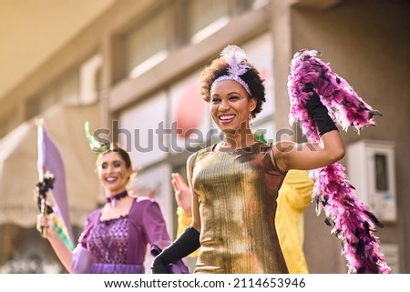 Happy African American woman in carnival costume having fun during Mardi Gras parade in the city. 