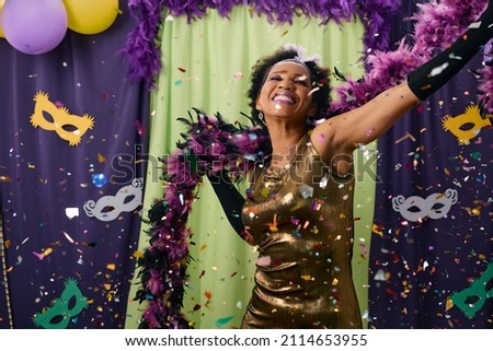 African American woman having fun while dancing among confetti on Mardi Gras party. 