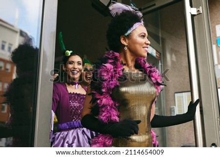 Happy African American woman and her friends wearing costumes while going on Mardi Gras carnival. 