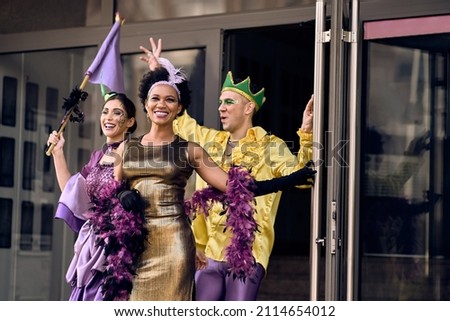 Happy African American woman and her friends wearing costumes and having fun while going on Mardi Gras street parade. 