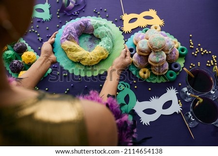 Close-up of woman setting the table for Mardi Gras celebration and serving King cake. 