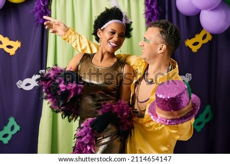 Happy African American woman and her male friend having fun while dancing at Mardi Gras party.