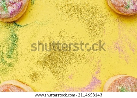 Flat lay of colorful Mardi Gras background with confetti and donuts. Copy space.