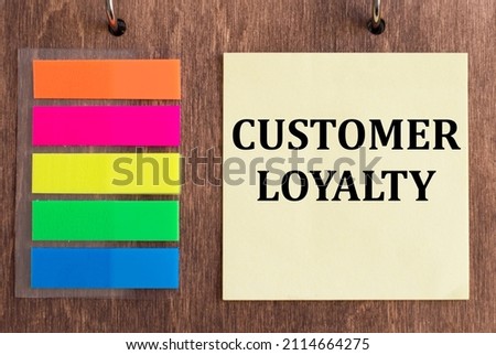 CUSTOMER LOYALTY tex on a yellow card on a wooden background next to colored stickers, business concept