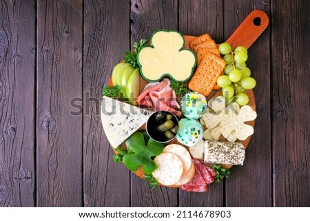 St Patricks Day theme charcuterie board against a wood background. Variety of cheese, meat, fruit and vegetable appetizers. Overhead view. Royalty-Free Stock Photo #2114678903